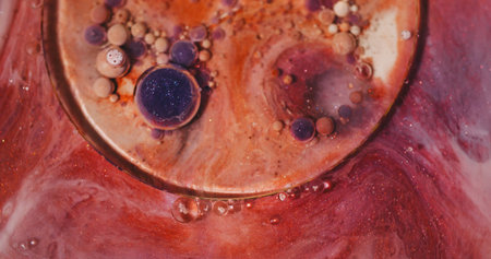 Ink stream. Oil bubbles. Defocused orange purple vibrant color glitter acrylic fluid round emulsion floating on abstract background.の写真素材