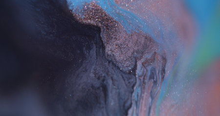 Blur ripple ink. Wet texture. Defocused orange purple blue color glitter chemical blotch floating on abstract dark black bokeh background.の写真素材