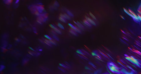 Defocused lens prism. Holographic glow leak. Spectrum color twinkle on night background. Purple red green neon blur abstract flash.の写真素材