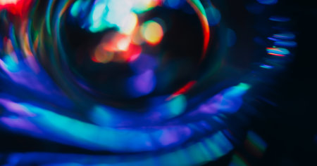 Light lens defocused. Holographic flare. Red green blue neon colorful luminosity on dark black background. Spectrum spin abstract optical effect.の写真素材