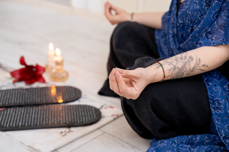 Woman practice yoga. Board sadhu. Sitting in lotus position mudra hands on mat in front of burning fire candles spiritual growth mental health.の写真素材