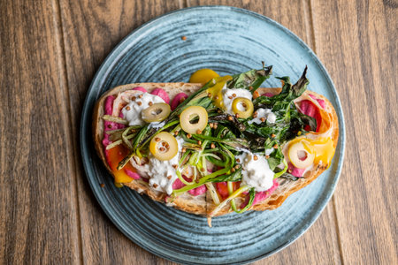 Gourmet toast. Nutrition food. Artisan bread with olive green leaves on plate. Portion meal with dripping bright sauce.の写真素材