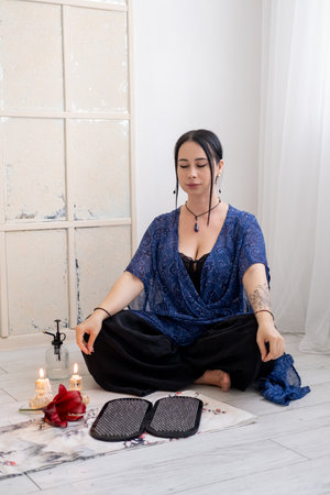 Woman practice yoga. Sitting in lotus position mudra hands before nails on mat in front of burning fire candles spiritual growth mental health.の写真素材