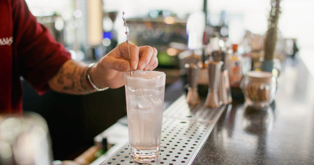 Preparing beverage. Cold drink. Barman hand decorating ice cube water with whipped white cream. Tall glass sweet lavender sprig flavor.の写真素材