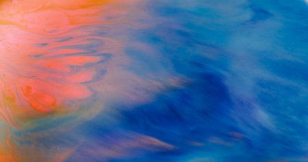 Blur dye stream. Ink spill. Orange acrylic emulsion flow on blue texture. Bright wave color mix liquid flow on abstract background.の写真素材