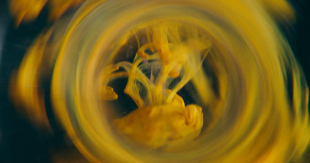 Dye blot blur. Vapor whirl. Circle color lens underwater splash. Yellow ink drop trickles spill on black abstract frame art background.の写真素材