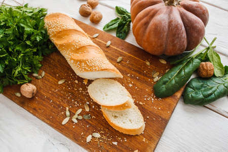 Crusty bread with vegetables on kitchen table. Ingredients for preparing tasty sandwiches with pumpkin, cucumbers and green. Snack, healthy food, vegetarian cuisine conceptの写真素材