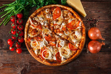 Traditional italian food. Delicious fresh pizza with tomatoes, chicken and onion on wooden background with ingredients, flat lay.の写真素材
