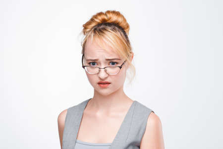 Young nice woman in glasses worried, upset and perplexed of problem. Unsolved situation, inability to concentrate, failure. Portrait on grey background.の写真素材