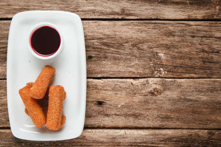 American fast food. Fried chicken nuggets on white plate served with sweet chili sauce, flat lay. Wooden background with copy space.の写真素材