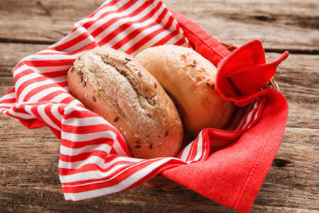 Two fresh bread buns in the basket on wooden table, close up view. Food background, menu photo.