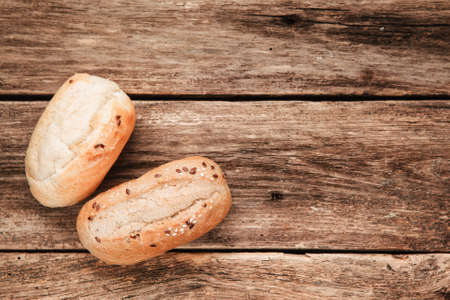 Food background of rustic wooden table with two fresh bread buns, flat lay. Free space for text, bakery conceptの写真素材
