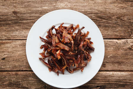Smoked spicy pig ears on white plate. Chinese food, tasty beer snacks served on rustic wooden table, top view. Restaurant menu photo.の写真素材