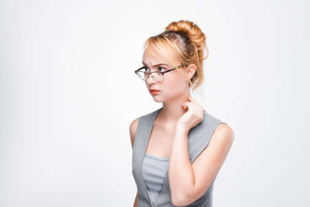Young nice woman concentrated on complicated issues, problems, personal troubles. Inability to solve the situation, mistrust, anxiety. Grey background with free space.の写真素材