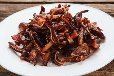 Unhealthy eating habits, junk food. Smoked pig ears served on white plate, close up view. Appetizing beer snackの写真素材
