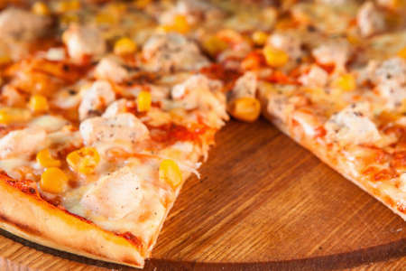 Delicious fresh italian pizza sliced and served on wooden rustic table with cut slice, close up view. Restaurant menu photo.の写真素材