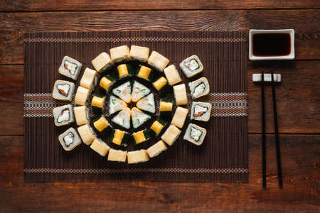 Japanese seafood cuisine. Delicious appetizing sushi set served on straw mat, on dark wooden table, flat lay. Food art, restaurant menu photo.の写真素材
