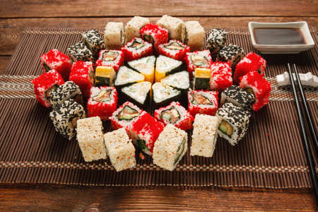 Food art, culinary masterpiece. Great set of sushi served in colorful ornament on brown straw mat, closeup. Luxury restaurant menu photo.の写真素材
