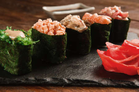 Fresh delicious set of five gunkan sushi served on black slate with ginger, closeup. Japanese healthy food, national cuisine. Restaurant menu photo.の写真素材