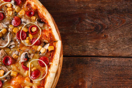 Traditional italian food. Appetizing pizza served on rustic wooden table. Dark background with copy space.の写真素材