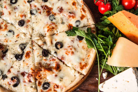 Delicious hot pizza sliced and served on wooden table with ingredients, top view. Restaurant menu photo.の写真素材