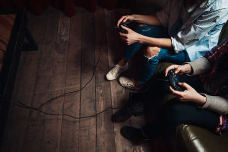Two unrecognizable girls with joysticks addicted to video game, try to beat high score. Inability to stop, psychological disorder, unhealthy lifestyle.の写真素材
