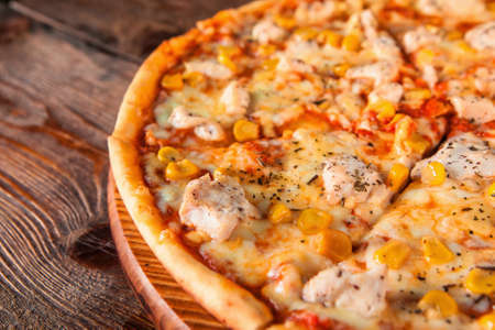Yummy fresh pizza sliced and served on wooden platter, close up view. Italian fast food.の写真素材