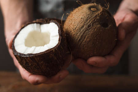 Hands holding fresh coconuts, close up. Culinary masterpiece, cosmetic recipe, organic food ingredient, tropical fruit conceptの写真素材