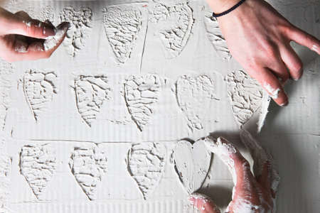 Creative art, hand make heart stamps on white plaster, flat lay. Stucco texture, decorative design,...
