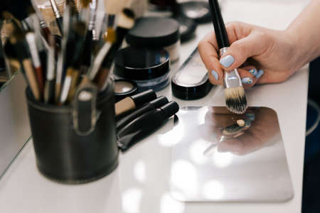 Hand of unrecognizable person holding a brush for makeup. The make-up artist prepares to apply a...