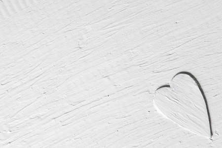 White romantic background with relief heart. Grungy handmade plaster surface, rough texture. Love, passion, amour, valentine day concept.の写真素材