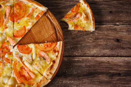 Fresh italian pizza with cut in slices served on rustic wooden table, flat lay. Calories, junk food, bad habits. Dark wooden background with free space for text.の写真素材