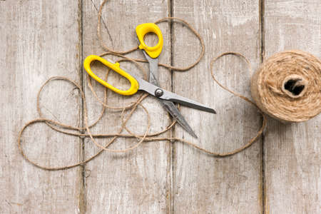 Scissors and rope on wooden background. Top view on workplace with diy tools. Decoration equipment, florist, decorator, handmade concept.の写真素材
