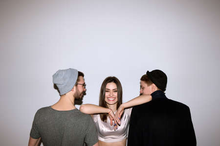 Happy girl in relationship with two men. Competition of boyfriends, polygamy, parthership of youth, friendship, family, party, first date conceptの写真素材