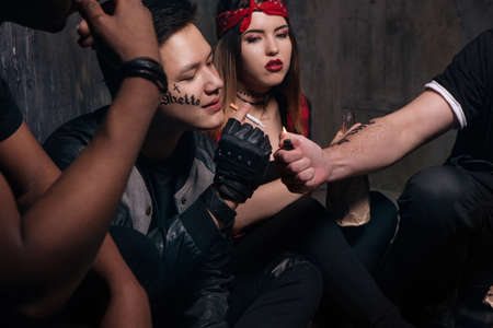 Nicotine addiction. Young tattooed guy smokes. Social problem concept. Gung member with drugs, outlaw lifestyleの写真素材