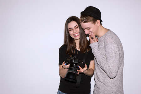 Happy couple enjoy with digital camera on white background. Female photographer show to male model photos. Woman and man laugh. Friendship of sexes, lifestyle, leisure, hobby conceptの写真素材