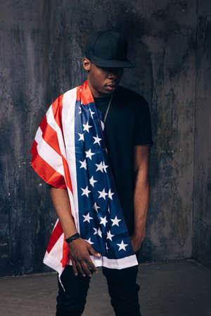Afro american man with american flag on dark background. Patriot, national event celebration, independence day, pride, usa citizen conceptの写真素材