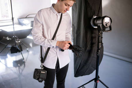 Young photographer work in studio. Man is setting photographing equipment in studio getting ready for a photo shootの写真素材