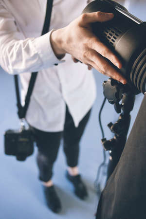 Unrecognizable man adjusting the light in studio. Photographer work with photo equipment in studio getting ready for a photoshootの写真素材
