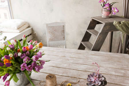 Floristry workplace background. Colorful flowers, tools set in white interior. Florist, decorator,...