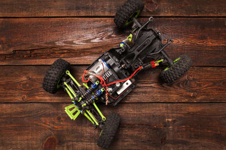 Rc radio control car model on wooden background. Green toy suv on table, top view