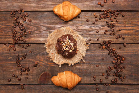 Roasted coffee beans frame and desserts on wooden background. Closeup of seeds on dark brown cafe table. Top view.の写真素材
