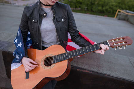Musician with the American flag playing the guitar. Acoustic concert on the roof. A teenager on...
