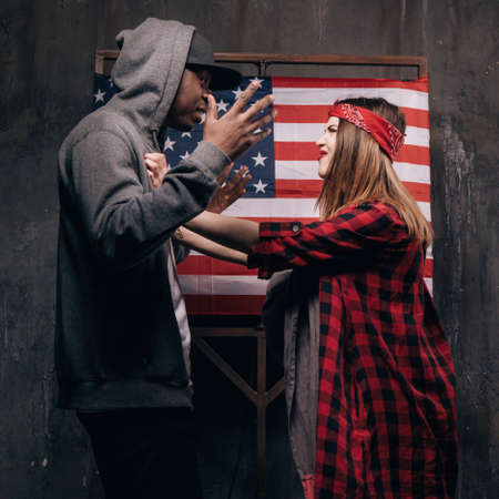Man and woman in conflict on US flag backdrop. Divorce in american family. Wife and husband with...