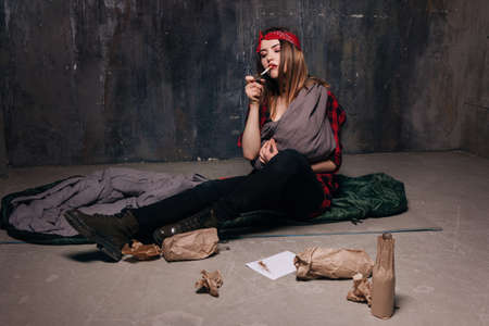 Poor nicotine and alcohol addicted mother smokes. Woman holding cigarette in mouth. Maternal harm, youth lifestyle, social problem, negative addiction conceptの写真素材