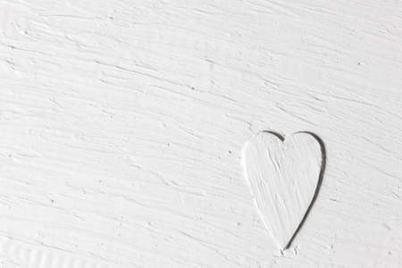 Love backdrop, white relief heart on rough stucco surface. Abstract handmade plaster background with free space for text.の写真素材