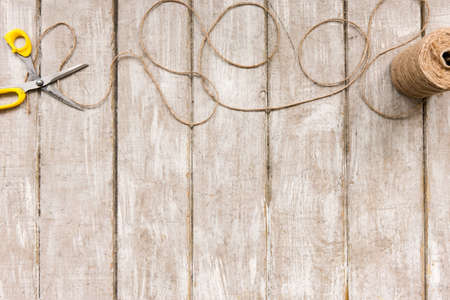 Scissors and rope ornament top view. Flat lay of workplace with diy tools on wooden background. Decoration equipment, florist, decorator, handmade concept.の写真素材