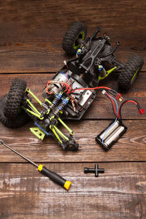 Dismantled broken Rc radio control car crawler model toy repair. Green toy suv in repairshop workplace, top viewの写真素材