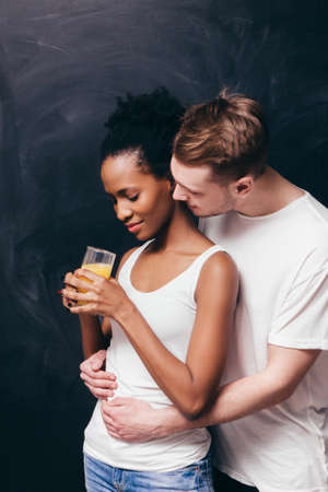 Interracial young couple, black woman and white man. Togetherness, tenderness, hug and care. Waiting for baby, pregnancy, happy parenthood conceptの写真素材