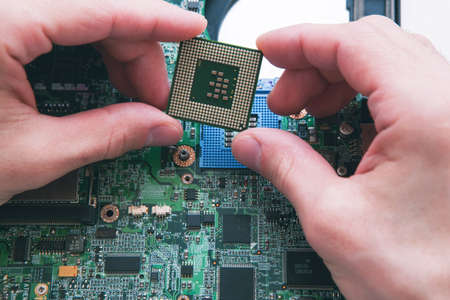 Technician analysis and plug in CPU microprocessor to motherboard socket. Workshop background